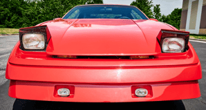 alt="Front view, with headlights up, of a 1987 Pontiac Firebird Tojan"