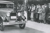 alt="Vintage photo of a Ford vehicle in a parade"