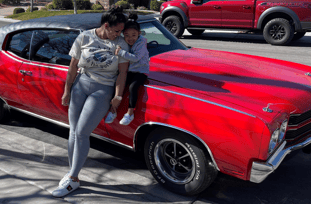 alt="Woman and child in front of a red 1970 Chevrolet Chevelle Malibu"